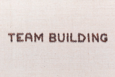 The words Team Building written with coffee beans on creamy linea canvas, shot from above, aligned in the center,close up.の写真素材
