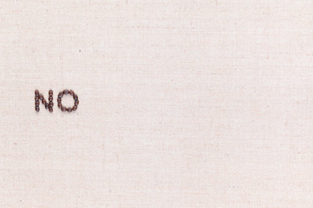 The word No written with coffee beans on creamy linea canvas, shot from above, aligned to the left.の写真素材