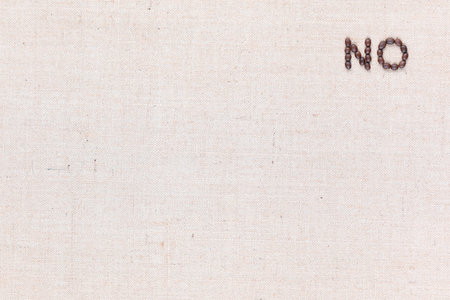 The word No written with coffee beans on creamy linea canvas, shot from above, aligned at the top right.の写真素材