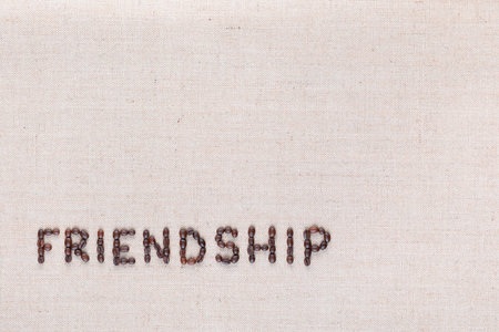Friendship word written with coffee beans on creamy linea canvas, shot from above, aligned at the bottom left.の写真素材
