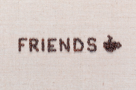 The word friends next to a hot coffee mug all made up from coffee beans ,aligned in the center,close up.の写真素材