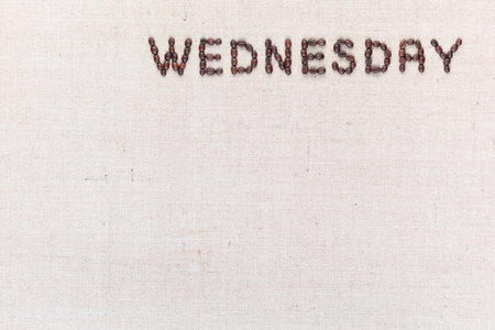 The word Wednesday written with coffee beans on creamy linea canvas, shot from above , aligned at the top right.の写真素材