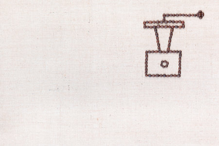 A coffee grinder made from coffee beans on creamy linea canvas, shot from above , aligned at the top right.の写真素材