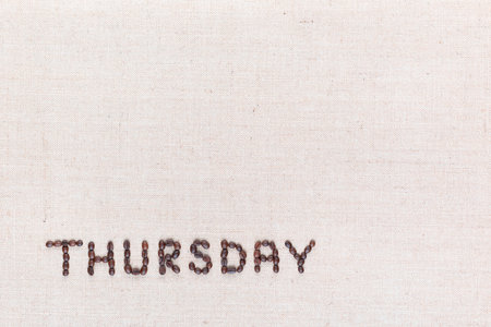 The word Thursday written with coffee beans on creamy linea canvas, shot from above , aligned at the bottom left.の写真素材
