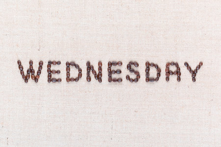 The word Wednesday written with coffee beans on creamy linea canvas, shot from above , aligned in the center, closeup.の写真素材