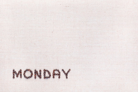 The word Monday written with coffee beans on creamy linea canvas, shot from above , aligned at the bottom left.の写真素材