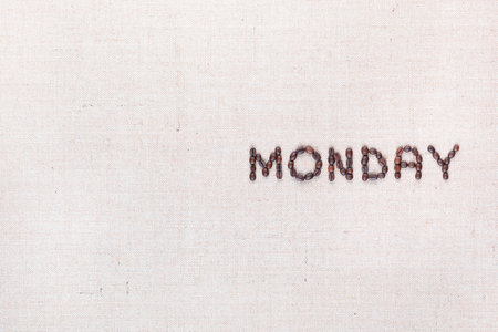 The word Monday written with coffee beans on creamy linea canvas, shot from above , aligned to the right.の写真素材