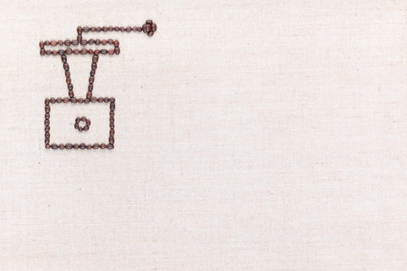 A coffee grinder made from coffee beans on creamy linea canvas, shot from above , aligned at the top left.の写真素材