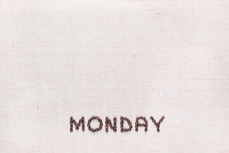 The word Monday written with coffee beans on creamy linea canvas, shot from above , aligned at the bottom.の写真素材