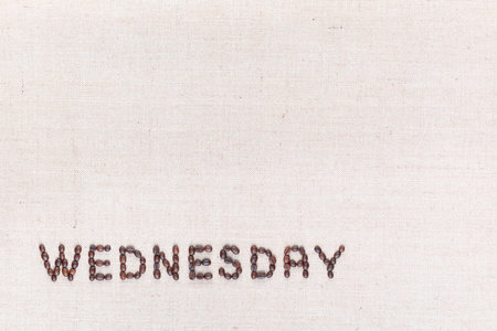 The word Wednesday written with coffee beans on creamy linea canvas, shot from above , aligned at the bottom left.の写真素材