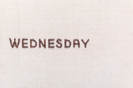 The word Wednesday written with coffee beans on creamy linea canvas, shot from above , aligned to the left.の写真素材