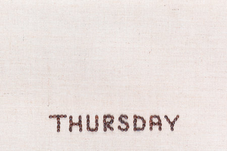 The word Thursday written with coffee beans on creamy linea canvas, shot from above , aligned at the bottom.の写真素材