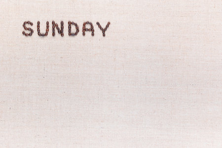 The word Sunday written with coffee beans on creamy linea canvas, shot from above, aligned at the top left.の写真素材