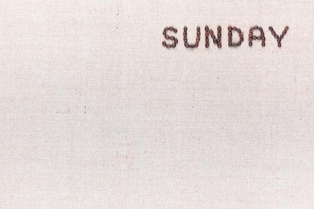 The word Sunday written with coffee beans on creamy linea canvas, shot from above, aligned at the top right.の写真素材