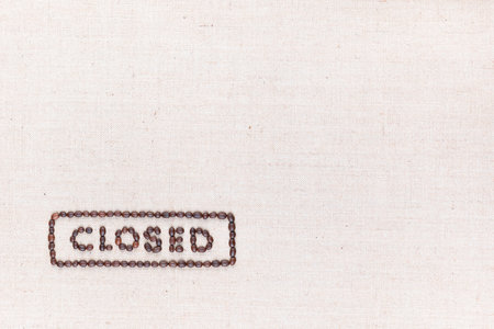 The word Closed inside a rectangle written with coffee beans on creamy linea canvas, shot from above, aligned at the bottom left.の写真素材