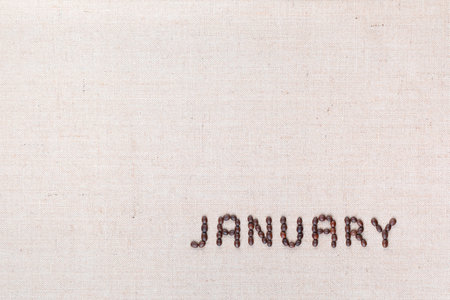 The word January written with coffee beans on creamy linea canvas, shot from above, aligned at the bottom right.の写真素材