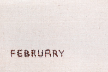 The word February written with coffee beans on creamy linea canvas, shot from above, aligned at the bottom left.の写真素材