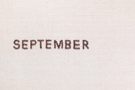 The word September written with coffee beans on creamy linea canvas, shot from above, aligned to the left.の写真素材
