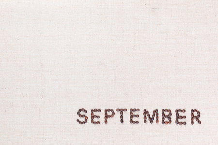 The word September written with coffee beans on creamy linea canvas, shot from above, aligned at the bottom right.の写真素材