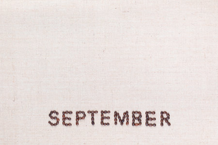 The word September written with coffee beans on creamy linea canvas, shot from above, aligned at the bottom.の写真素材