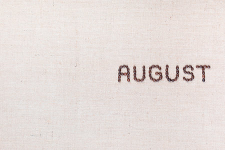 The word August written with coffee beans on creamy linea canvas, shot from above, aligned to the right.の写真素材