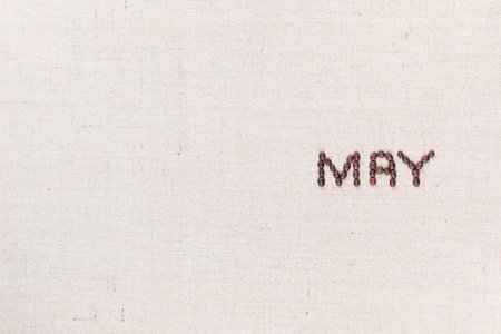 The word May written with coffee beans on creamy linea canvas, shot from above, aligned to the right.の写真素材