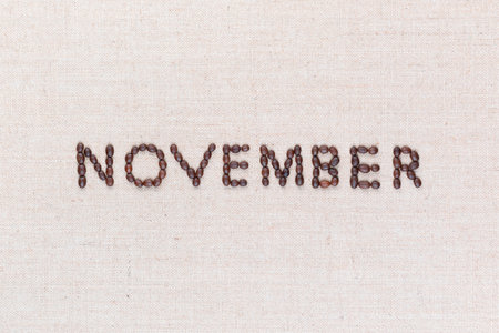 The word November written with coffee beans on creamy linea canvas, shot from above, aligned in the center, closeup.の写真素材