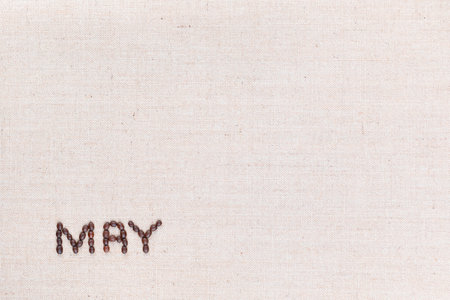 The word May written with coffee beans on creamy linea canvas, shot from above, aligned at the bottom left.の写真素材