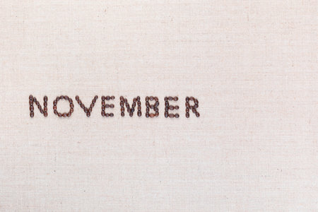 The word November written with coffee beans on creamy linea canvas, shot from above, aligned to the left.の写真素材