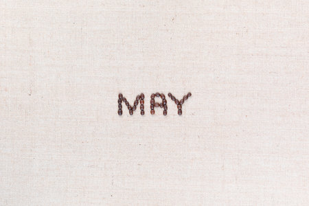 The word May written with coffee beans on creamy linea canvas, shot from above, aligned in the center.の写真素材