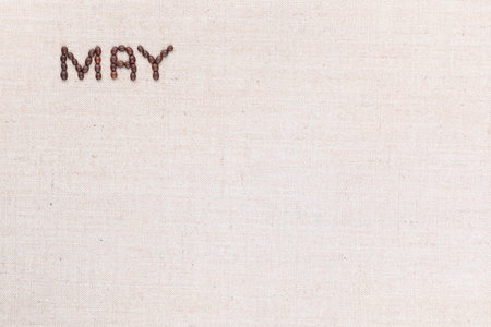 The word May written with coffee beans on creamy linea canvas, shot from above, aligned at the top left.の写真素材