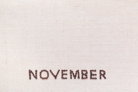 The word November written with coffee beans on creamy linea canvas, shot from above, aligned at the bottom.の写真素材