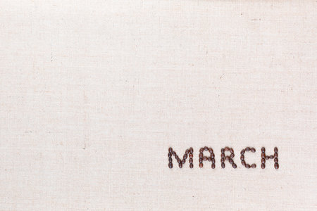 The word March written with coffee beans on creamy linea canvas, shot from above, aligned at the bottom right.の写真素材