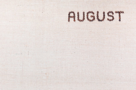 The word August written with coffee beans on creamy linea canvas, shot from above, aligned at the top right.の写真素材