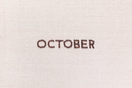 The word October written with coffee beans on creamy linea canvas, shot from above, aligned in the center.の写真素材