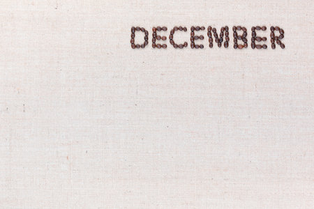 The word December written with coffee beans on creamy linea canvas, shot from above, aligned at the top right.の写真素材