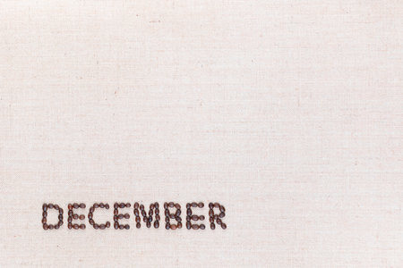 The word December written with coffee beans on creamy linea canvas, shot from above, aligned at the bottom left.の写真素材
