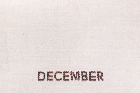 The word December written with coffee beans on creamy linea canvas, shot from above, aligned at the bottom.の写真素材