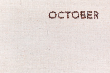 The word October written with coffee beans on creamy linea canvas, shot from above, aligned at the top right.の写真素材