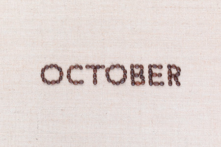 The word October written with coffee beans on creamy linea canvas, shot from above, aligned in the center, closeup.の写真素材