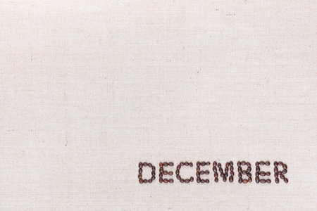 The word December written with coffee beans on creamy linea canvas, shot from above, aligned at the bottom right.の写真素材
