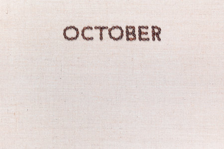 The word October written with coffee beans on creamy linea canvas, shot from above, aligned at the top.の写真素材