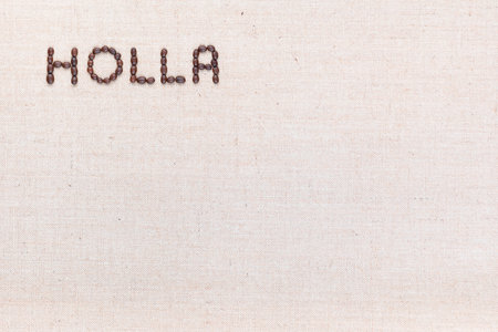 The word Holla written with coffee beans on creamy linea canvas, shot from above, aligned at the top left.の写真素材