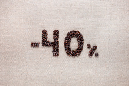 Roasted coffee beans shaping 40% off writing on creamy linen background, aligned in centerの写真素材