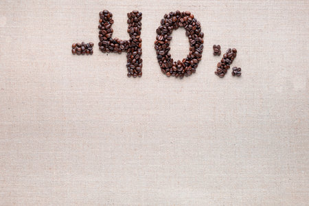 Roasted coffee beans shaping 40% off writing on creamy linen background, aligned top centerの写真素材