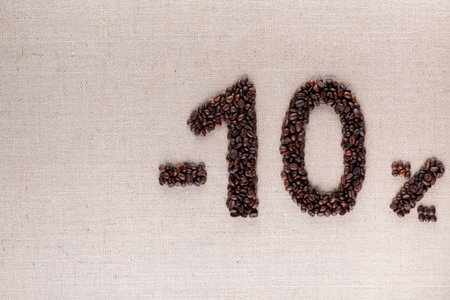 Roasted coffee beans shaping 10% off writing on creamy linen background, aligned middle rightの写真素材
