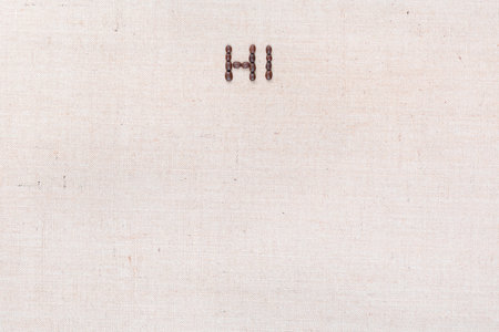 The word Hi written with coffee beans on creamy linea canvas, shot from above, aligned at the top.の写真素材