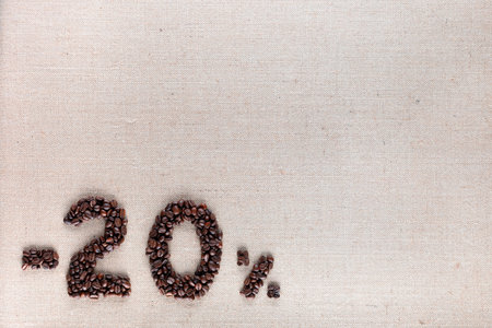 Roasted coffee beans shaping 20% off writing on creamy linen background, aligned bottom leftの写真素材