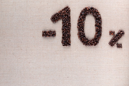 Roasted coffee beans shaping 10% off writing on creamy linen background, aligned at the top rightの写真素材