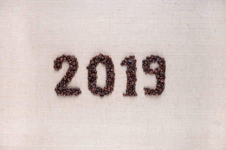 Bunch of fresh roasted coffee beans forming 2019 inscription on creamy linen canvas, aligned in centerの写真素材